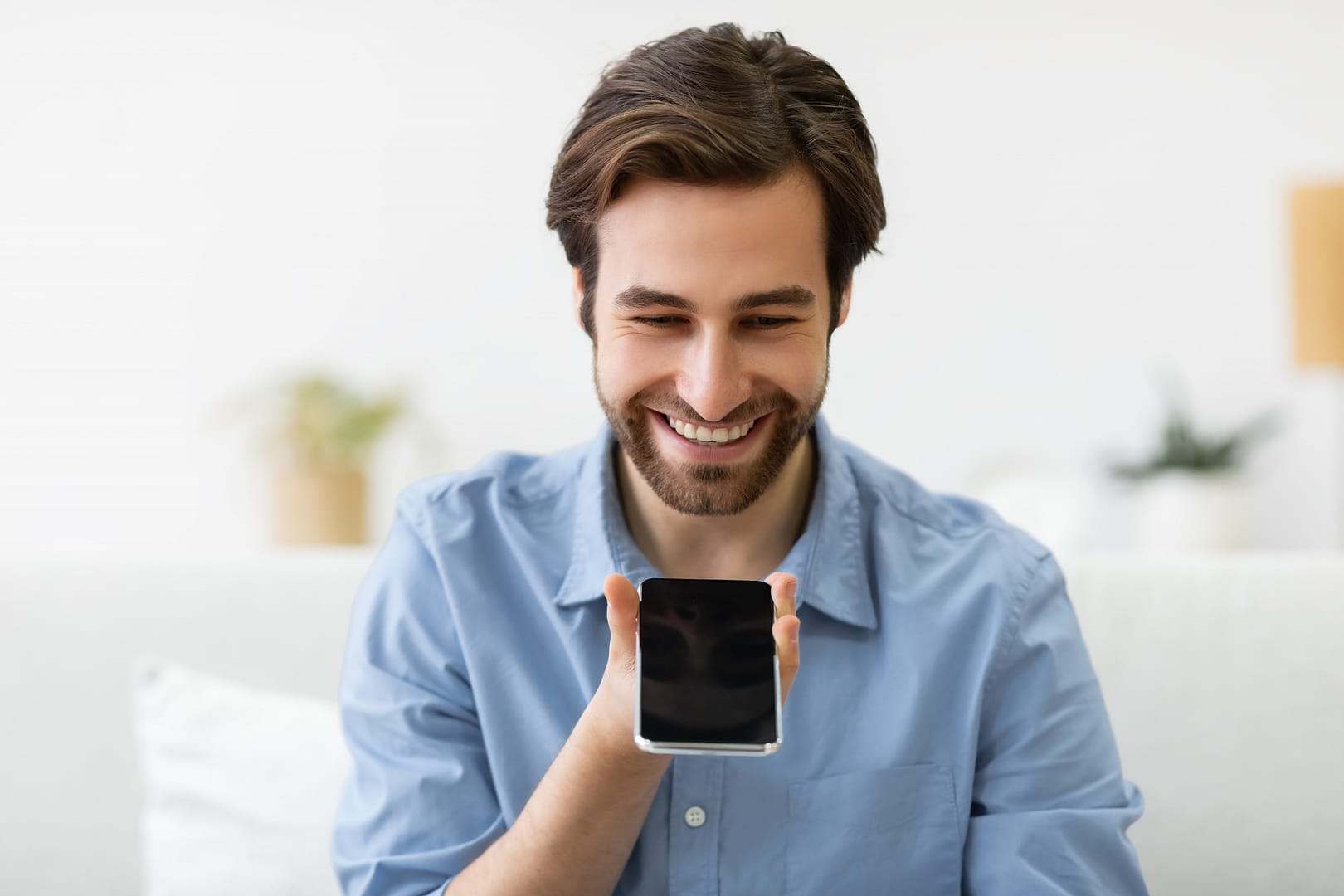 Cheerful Man Using Smartphone With Voice Search Application Sitting Indoor